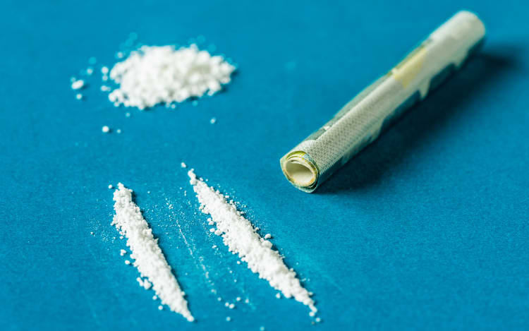 Rolled-up bank note being used to snort a line of cocaine.